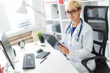 Genç bir kız bir beyaz robe oturma masa ve dolgular bir belge