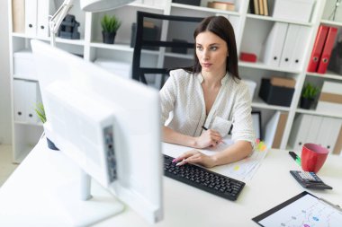 Office belgeleri ve bir bilgisayar ile çalışan bir genç kız. Masada genç bir kızın portresi.