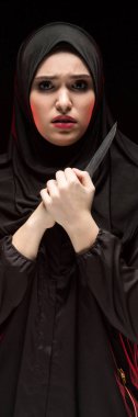 Elinde bıçakla ona teslim olarak koruma kavramı siyah arka plan üzerine siyah hijab giyen korkmuş genç Müslüman kadın portresi güzel umutsuz korkuttu
