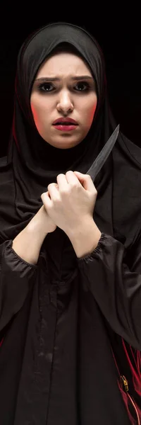 Πορτρέτο του όμορφη απελπισμένος φοβάται φοβισμένη νεαρή μουσουλμάνα φορώντας μαύρο χιτζάμπ κρατώντας το μαχαίρι στα χέρια της ως έννοια προστασία σε μαύρο φόντο — Φωτογραφία Αρχείου