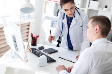 Doktor hastaya bilgisayarda sorunu anlatan.