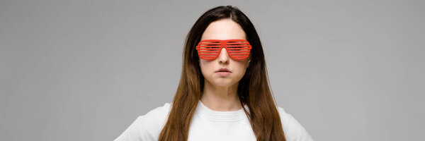 Портрет эмоциональной красивой успешной модели плюс размер в солнцезащитных очках, стоящих в студии и смотрящих в позу камеры
