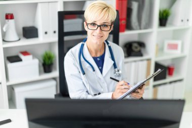 Genç bir kız bir beyaz robe oturma masa ve dolgular bir belge