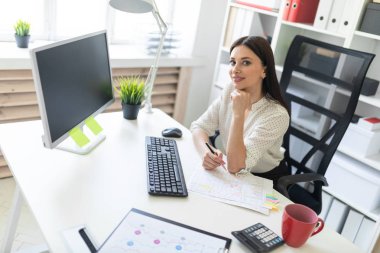 Office belgeleri ve bir bilgisayar ile çalışan bir genç kız. Masada genç bir kızın portresi.