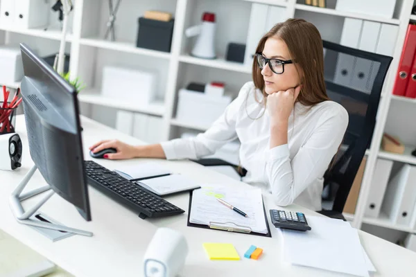 Jong meisje zitten aan de tafel en het werken met een computer, documenten en calculator — Stockfoto