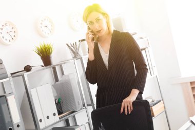 Bir genç kız ofiste ayakta ve telefonda konuşurken.