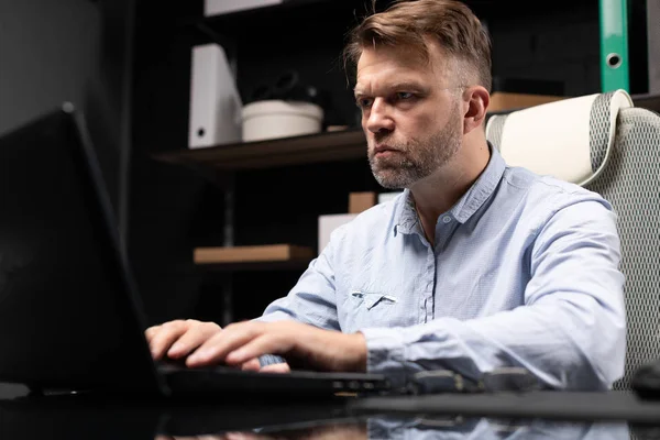 Serious businessman typing on laptop in stylish, modern office — Stock Photo, Image