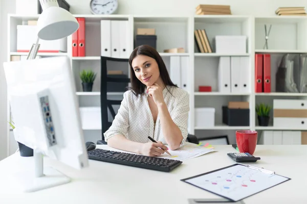 Een jong meisje werken in het kantoor met documenten en een computer. Portret van een jong meisje aan tafel. — Stockfoto