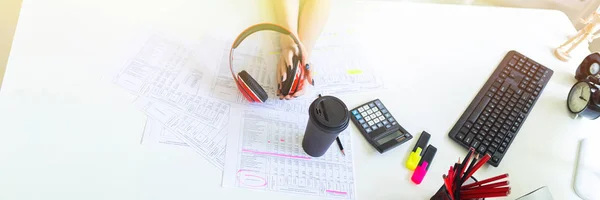 Menina bonita com fones de ouvido nas mãos está sentado no escritório na mesa . — Fotografia de Stock