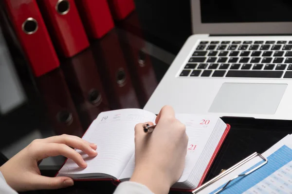 Close-up van handen maken van aantekeningen in dagboek naast tabletcomputer — Stockfoto