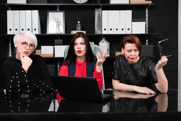 Tres compañeras sentadas en la oficina a la mesa con portátil — Foto de Stock