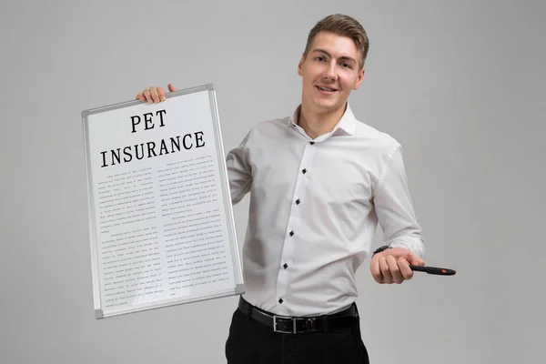 Young man holding poster with pet insurance isolated on light background