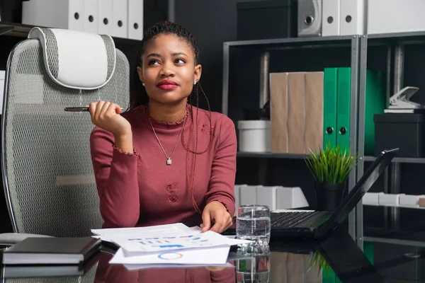 Retrato de una joven mujer de negocios negra que trabaja con gráficos y diagramas en el escritorio en la oficina — Foto de Stock