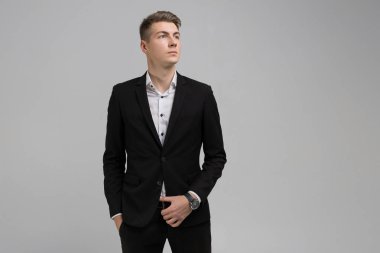 Elleri ceplerinde izole beyaz arka plan üzerinde siyah elbiseli olan genç adam portresi