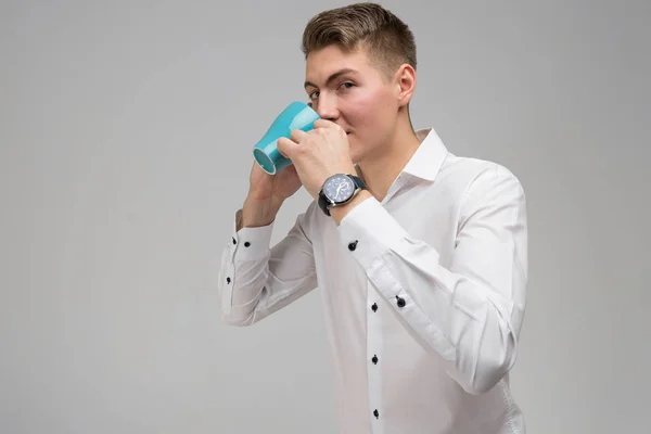 Retrato de jovem com caneca e telefone celular em suas mãos isolado no fundo branco — Fotografia de Stock