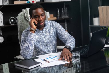 cep telefonu bilgisayar ofis masasında oturan konuşurken genç siyah işadamı