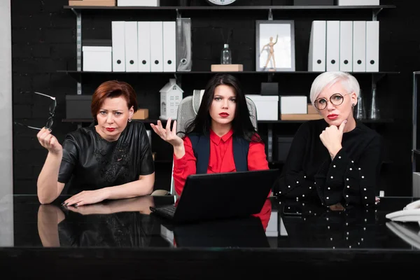 Tres compañeras sentadas en la oficina a la mesa con portátil — Foto de Stock