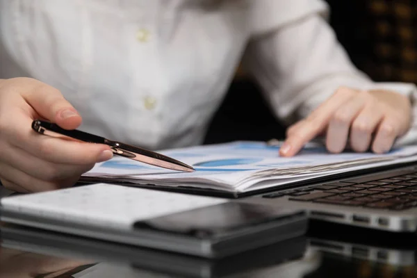 Female hands work with chart on a background of notebook Royalty Free Stock Images