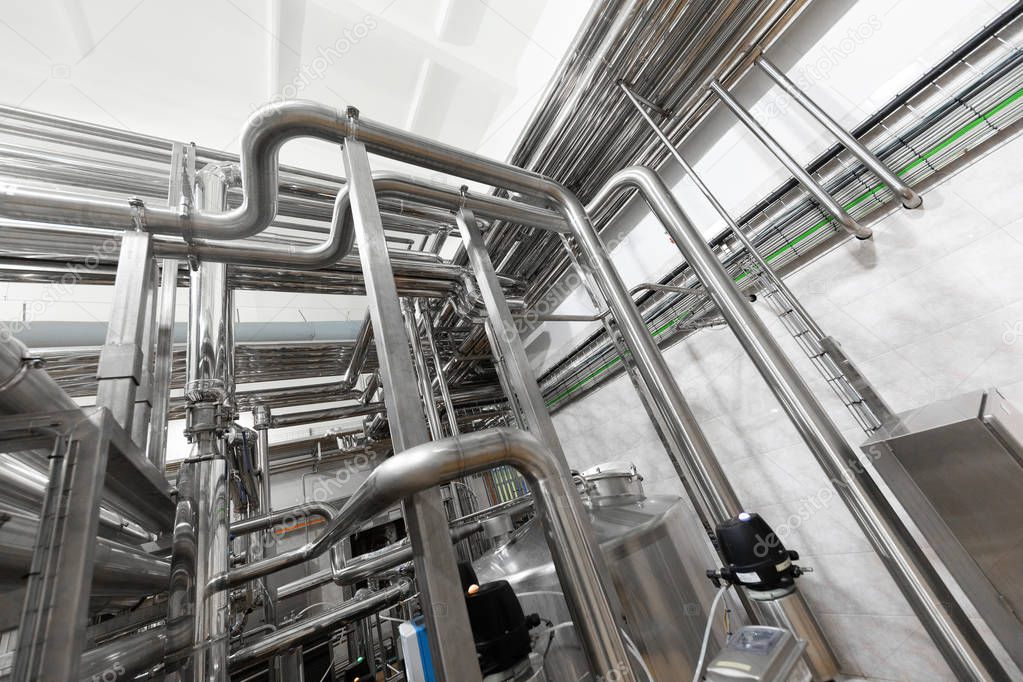 Industrial pipelines and modern equipment in cheese production interior