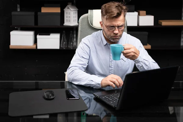 Serious businessman working on laptop and drinking coffee — Stock Photo, Image