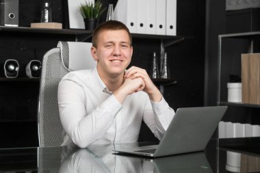 Genç adam ofiste dizüstü bilgisayarla çalışıyor.