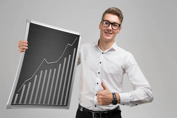 Young man shows class sign and keeps rising graph isolated on white background — Stock Photo, Image