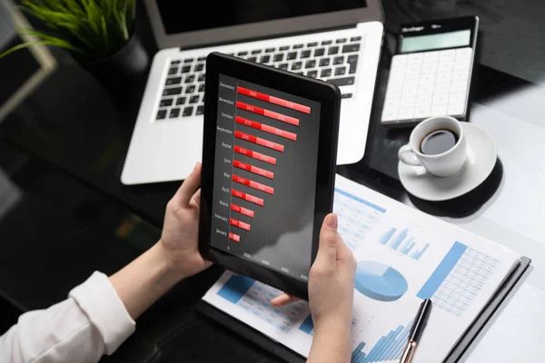 財務書類の背景にタブレットを保持しているクローズ アップ手 — ストック写真