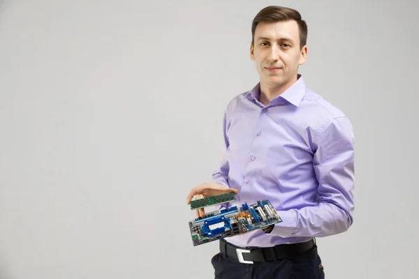 Young man holds the RAM and the motherboard in his hands isolated on a light background — Stock Photo, Image