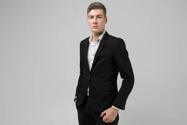 Portrait of young man with hands in pockets in black suit isolated on white background — Stock Photo, Image