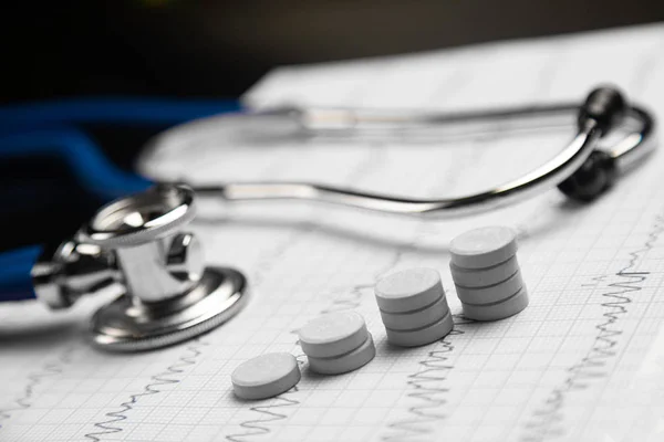 Stetoskop och trappor från tabletter ligga på ark med elektrokardiogram — Stockfoto