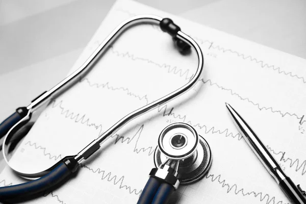 Stetoskop i pióra leżą na arkuszu z EKG — Zdjęcie stockowe