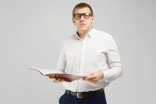 Joven en gafas con una carpeta abierta en las manos aislada sobre un fondo claro — Foto de Stock