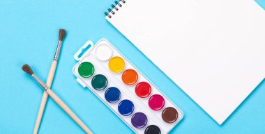 Aquarelle boya fırçaları ve albüm üzerinde mavi arka plan izole boyama için kümesi