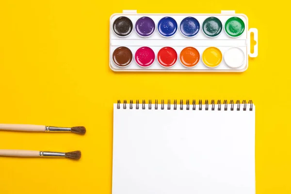Pinturas de acuarela y pinceles con lienzo para pintar con copyspace sobre fondo amarillo —  Fotos de Stock