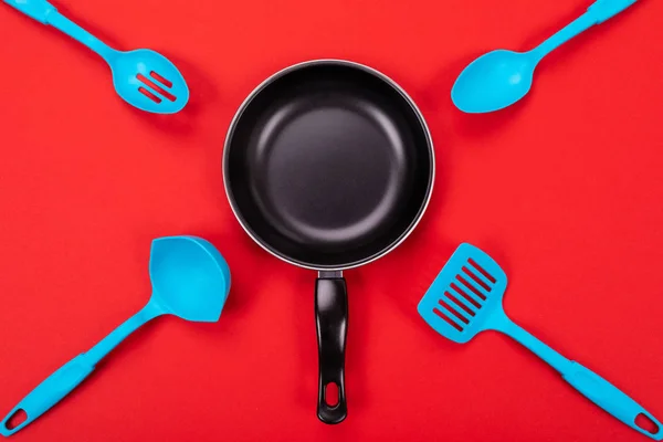 Keukengerei voor het koken in de keuken, geïsoleerd met copyspace op rode achtergrond — Stockfoto