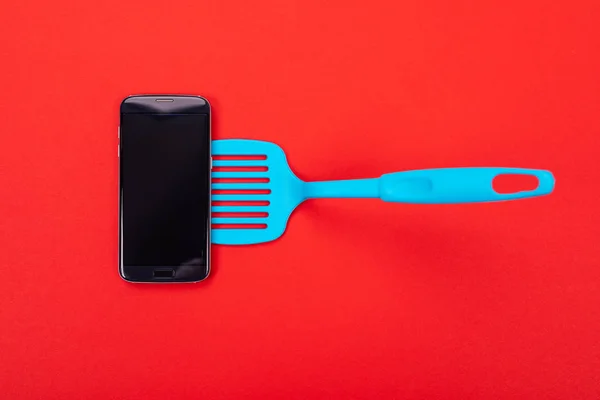 Top view of smart phone as part of cooking equipment in kitchen isolated on red background — Stock Photo, Image