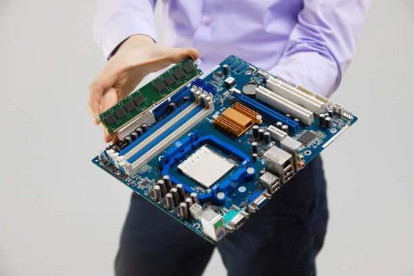 RAM and motherboard in mens hands close-up isolated on light background — Stock Photo, Image