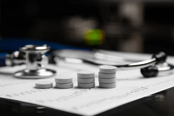 Stetoskop i schody z tabletek leżą na arkuszu z EKG — Zdjęcie stockowe