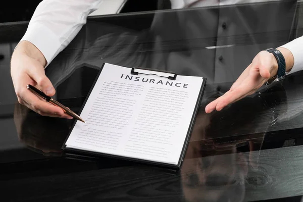 Hands with pen and insurance on table — Stock Photo, Image