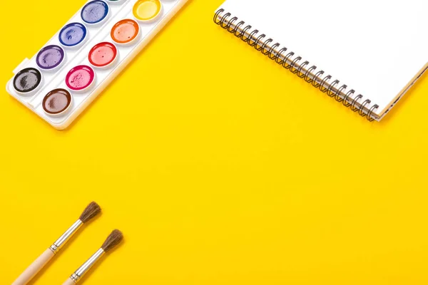 Pinturas de acuarela y pinceles con lienzo para pintar con copyspace sobre fondo amarillo —  Fotos de Stock