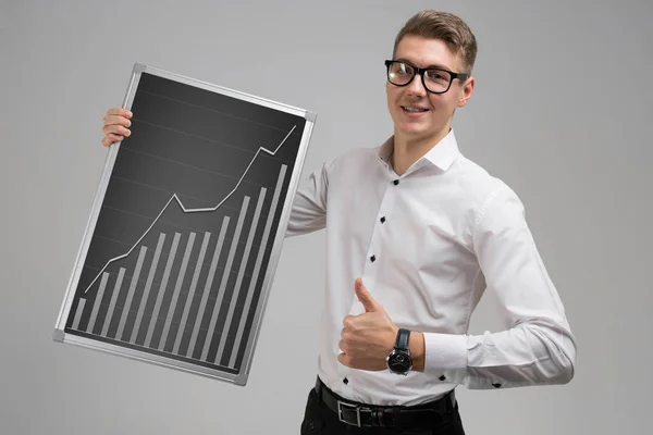 Young man shows class sign and keeps rising graph isolated on white background — Stock Photo, Image