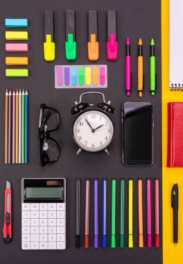 Flat lay composition of business desk with smartphone, calculator, stickers, and pens on colorful black and yellow background