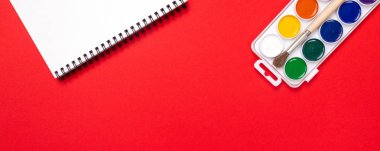 Suluboya boya ve fırça izole kırmızı arka plan üstten görünüm üzerinde albüm çizim ile