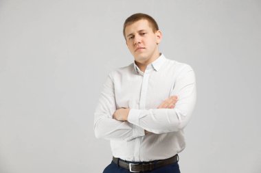 Göğüs üzerinde katlanmış silah ile izole üzerinde beyaz arka plan beyaz tişörtlü genç adam standları