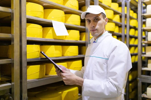Inspecteur maakt notities in het blad in het magazijn van kaas — Stockfoto