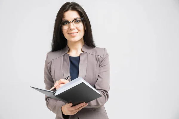 Portrait of a young girl with glasses with a diary in her hands isolated on a light background — Stock Photo, Image