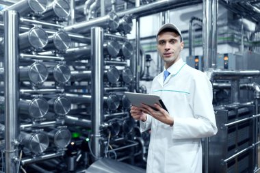 Teknoloji uzmanı bir beyaz önlük yapar gerekli girişleri tablet olarak fabrikada olduğunu. Dijital tablet üretim dükkanda üniformalı bir adam. üretim departmanı arka plan üzerinde iç