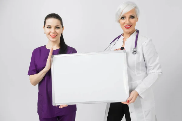 Doktor ve hemşire holding beyaz arka plan üzerinde izole bir boş manyetik Yönetim Kurulu — Stok fotoğraf
