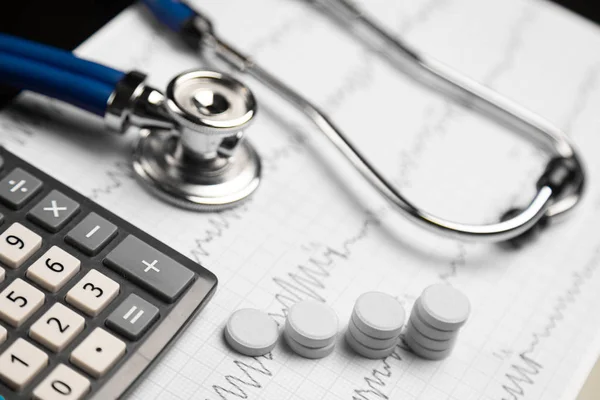 Stetoskop, piller och kalkylator är på ett blad med ett EKG — Stockfoto
