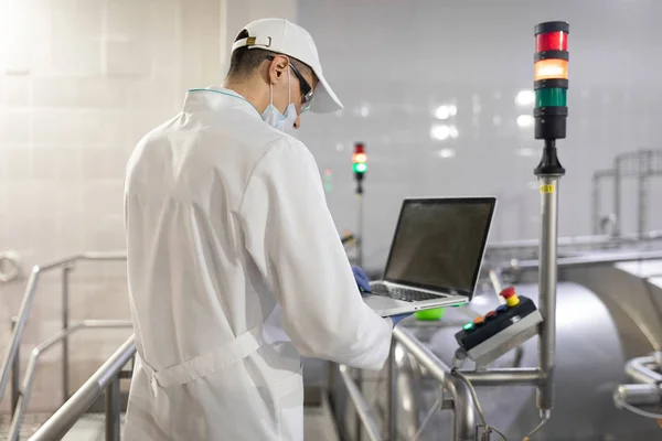 Un employé avec un ordinateur portable dans ses mains à l'usine laitière — Photo